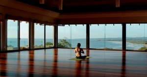 Woman sitting meditating in yoga studio with island view