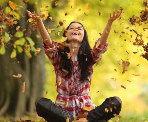 Lady throwing leaves in the air during fall