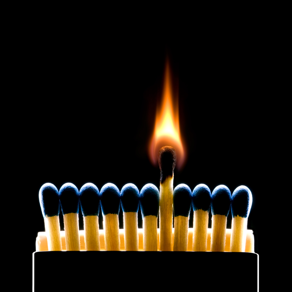 11 dark blue match sticks with the middle one on fire