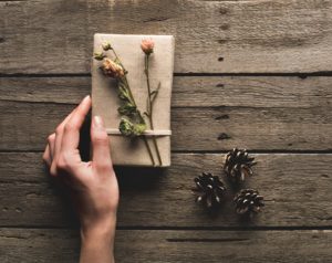 Woman's hand with a present wrapped with brown paper and dried flowers