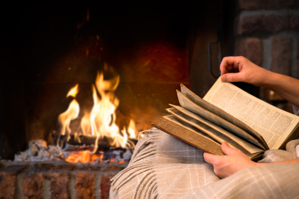 person reading a leadership book in front of a fire